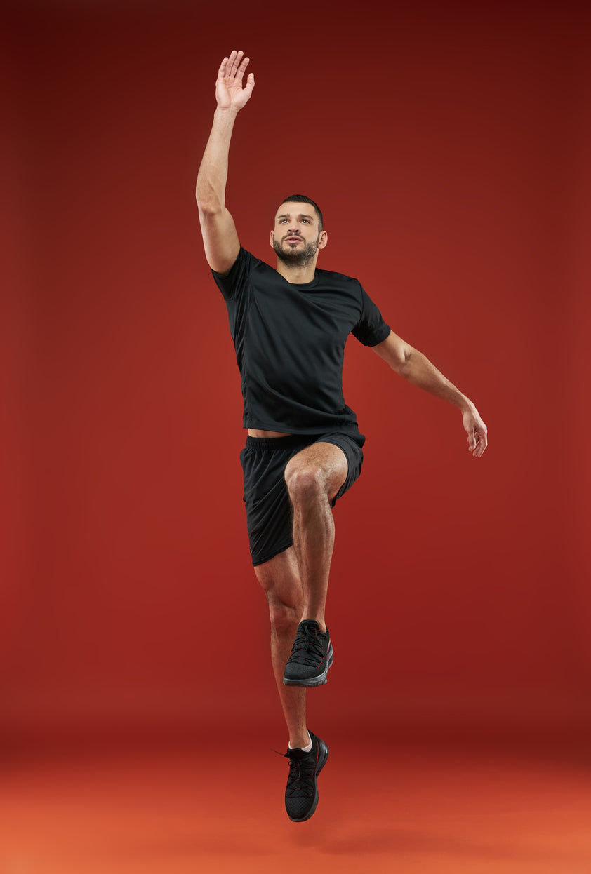 Man in black athletic wear posing against a red background